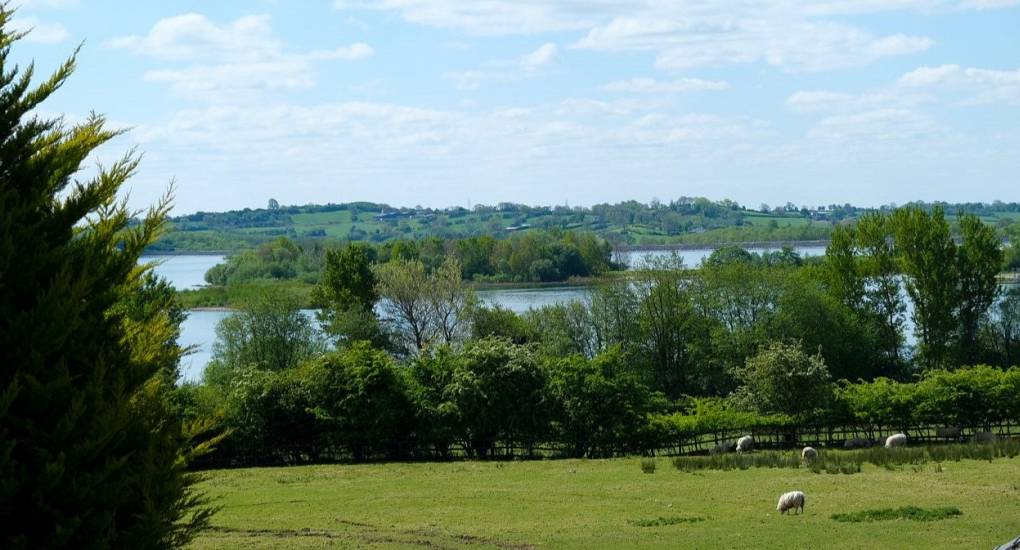 View from the gardens with lake and island across a field