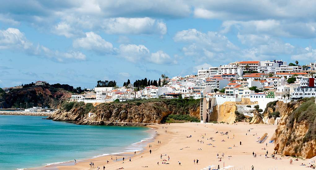 Golden sand beach and whitewashed cliffside buildings in Albufeira, set up for an unforgettable albufeira stag do.
