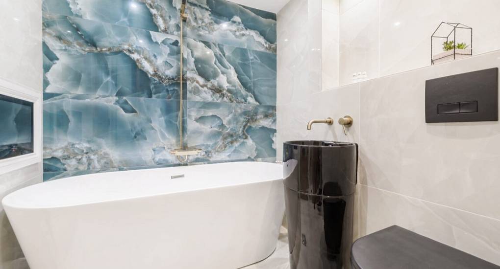 Modern bathroom with freestanding bath and marble effect splash wall