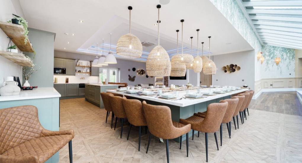Large dining table in open plan space with fully equipped kitchen in the back