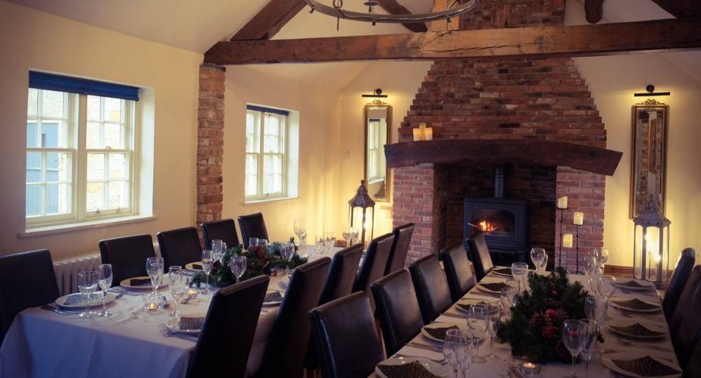 Anotehr view of the dining area with 2 table set up for an event with the open fire in the background