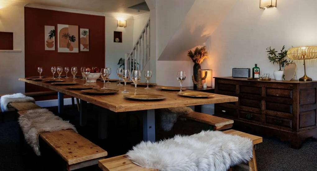 The long rustic dining table with faux fur throws at Autumn Cottage, a large Bath hen party house with hot tub for 26.