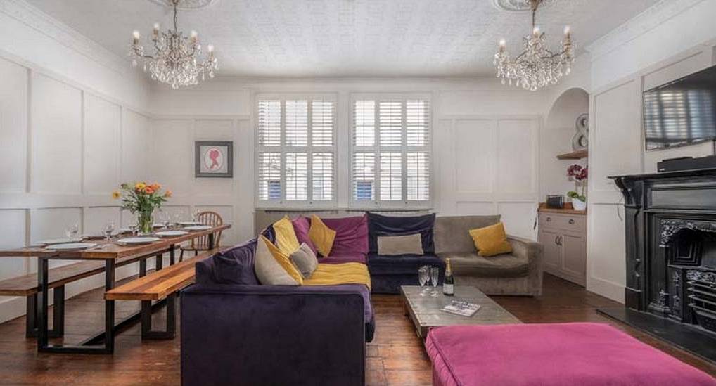 The Georgian panelled lounge with purple sofa and chandeliers at The Spas, a luxury central Bath hen apartment.