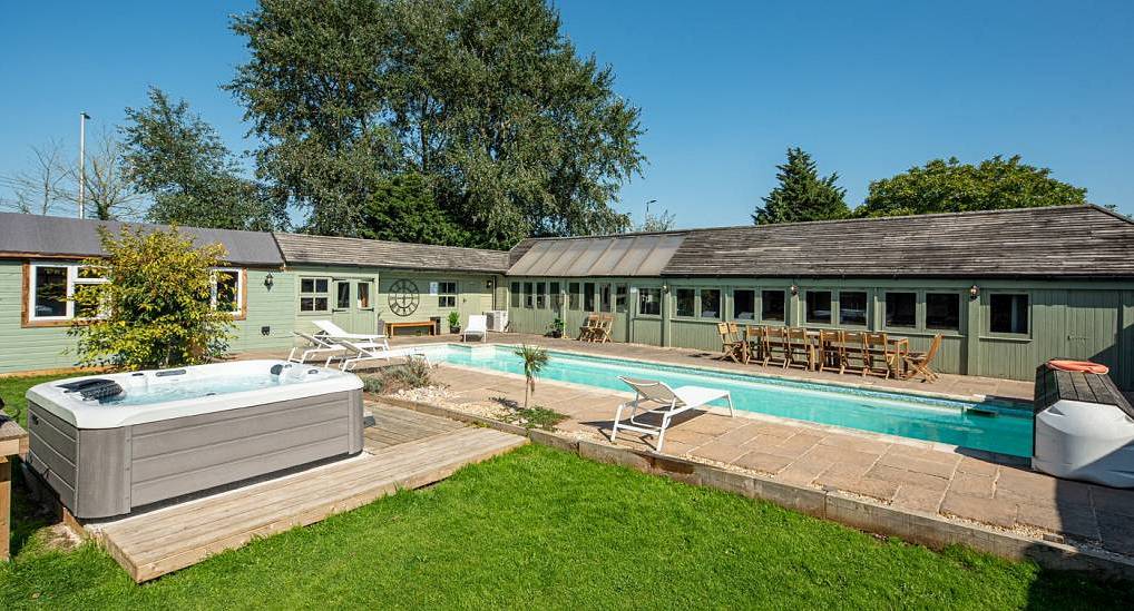 The outdoor heated lap pool and hot tub deck at The Villa, a Bath hen party house near Bristol sleeping 17.