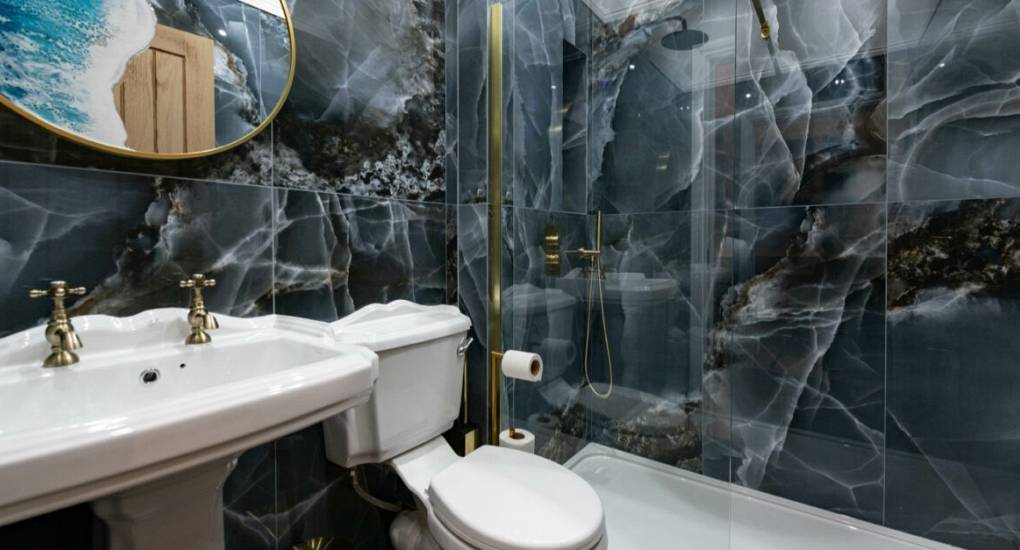 Modern black marble effect bathroom with white porcelain furnishings with gold fittings 