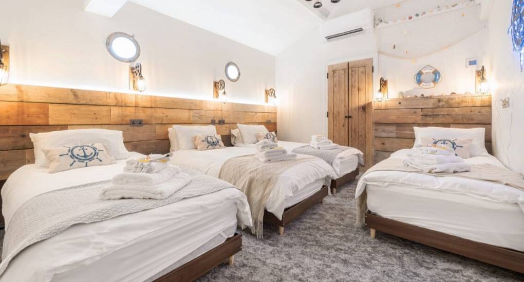 Bright bedroom with four made up beds 