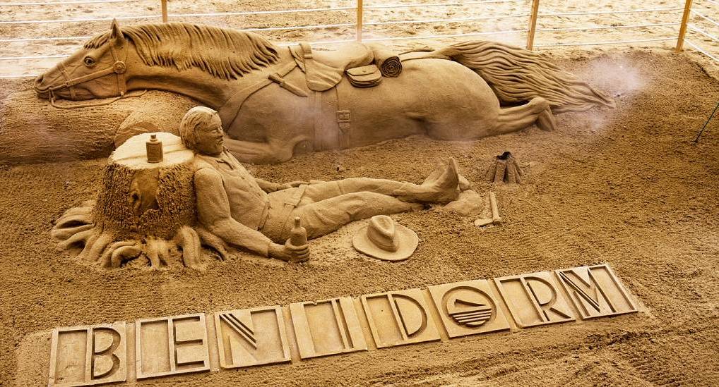 Impressive cowboy sand sculpture on the beach with BENIDORM text carved into sand, welcoming groups for a Benidorm stag do.