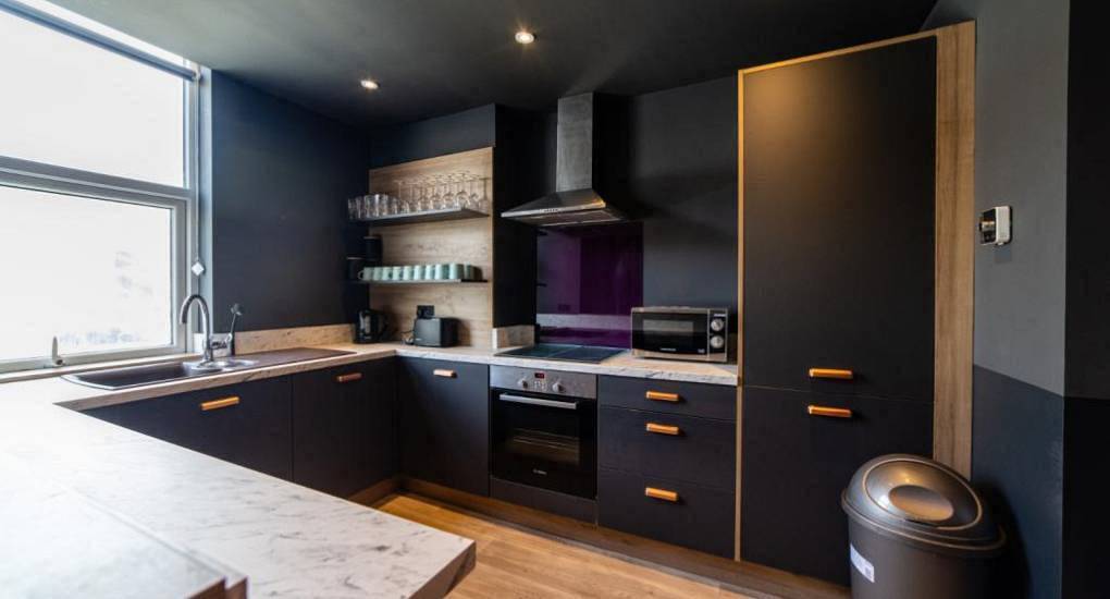 Sleek dark fitted kitchen at LA Suite, a luxury Hollywood-glamour Blackpool hen apartment sleeping 19 guests.