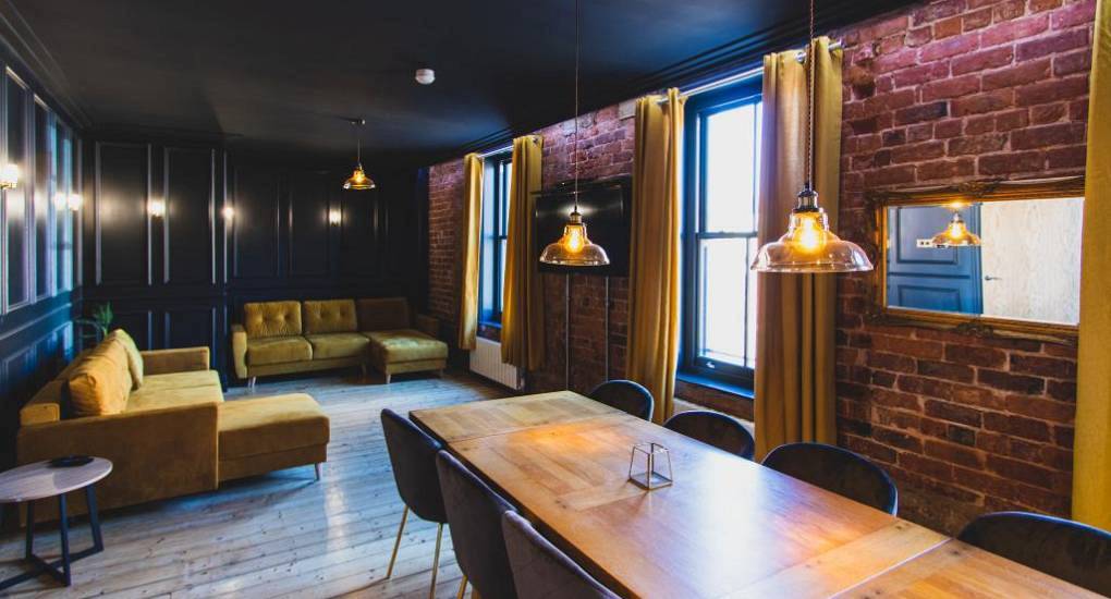 Exposed brick dining area and mustard velvet sofas at Renaissance, boutique Blackpool central hen apartments.