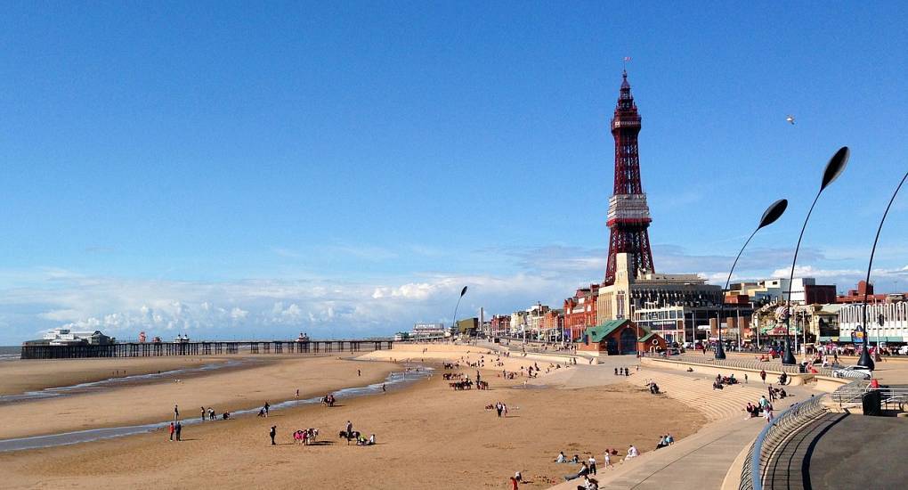 Iconic Blackpool Tower rising above Central Pier and sandy beach promenade, setting the stage for a Blackpool stag do.