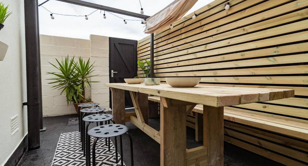 Outdoor patio dining area with bench seating at BH3 House, a Bournemouth hen party house near the beach.