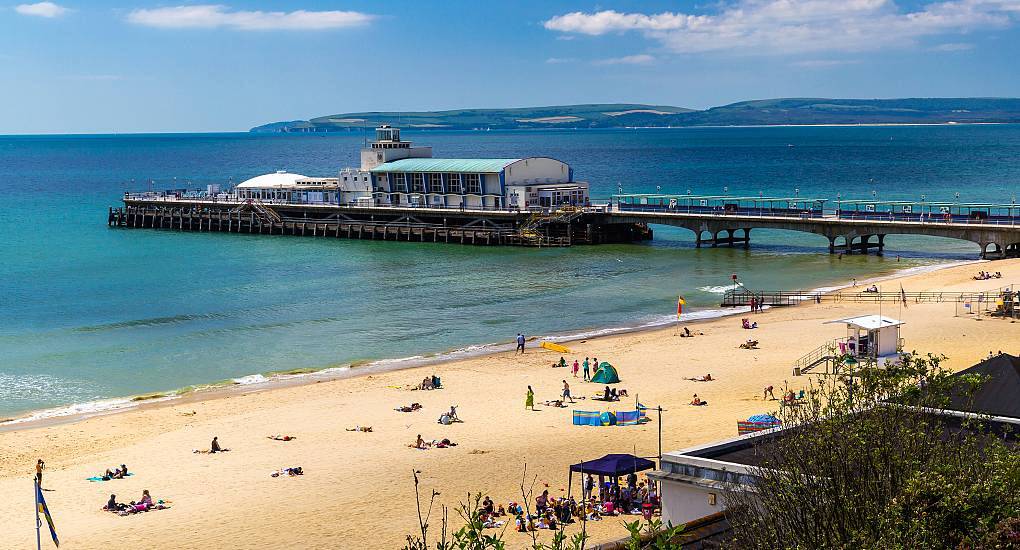 Sunny Bournemouth Pier extending into blue ocean waters from sandy beach, scenic backdrop for a Bournemouth hen do.