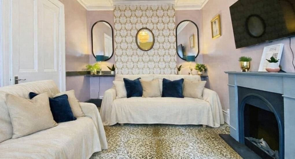 Bohemian lounge with upcycled furniture, open-style fireplace, and large TV at the Bournemouth Hot Tub Garden hen party house.