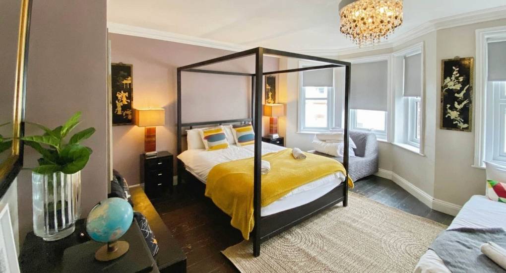 Spacious bohemian master bedroom with a four-poster bed and single chair bed, sleeping 3 guests.