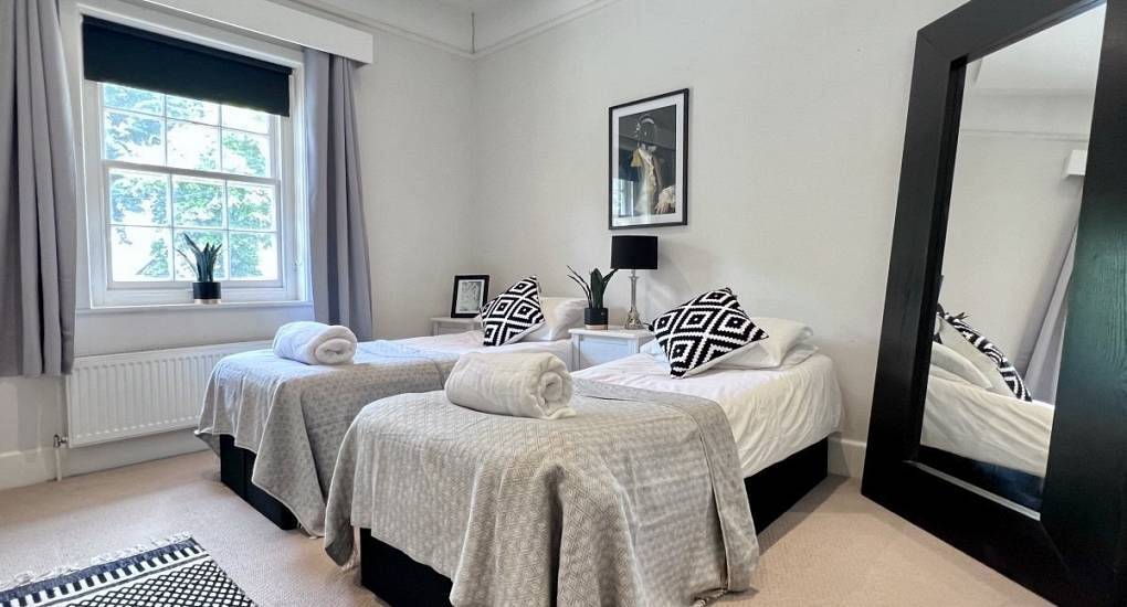 Modern twin bedroom with monochrome decor and large mirror at Sea Breeze, a massive Bournemouth hen house.