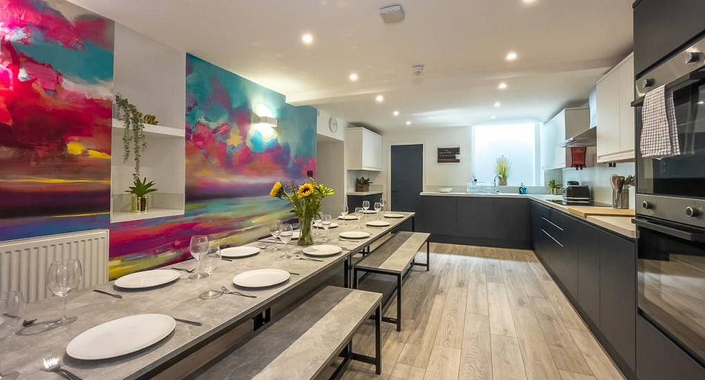 Colourful wall mural and long dining table in kitchen at Alanas House, central Brighton hen party house for 20.