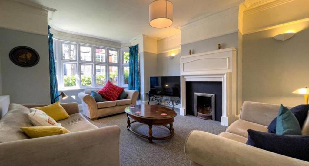 Spacious classic living room with plush sofas and bay window at The Clockworks, central Brighton hen party house.