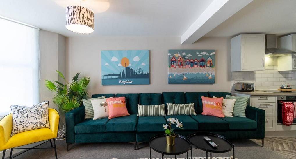 Plush teal velvet sofa and bright yellow armchair at Ethans Cabin, a relaxed 6-bedroom Brighton hen house.