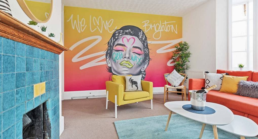 Vibrant We Love Brighton wall art, coral sofa, and blue tiled fireplace at Kemps Central, Kemptown hen party house.