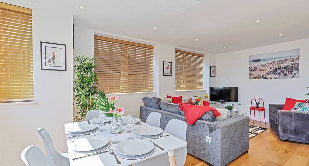 Light-filled open plan living and dining area with grey sofa and red accents at Metropolitan, central Brighton hen house.