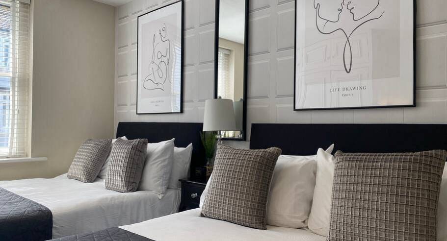 Boutique twin bedroom with line art prints and check cushions at Monochrome House, luxury Brighton hen townhouse.