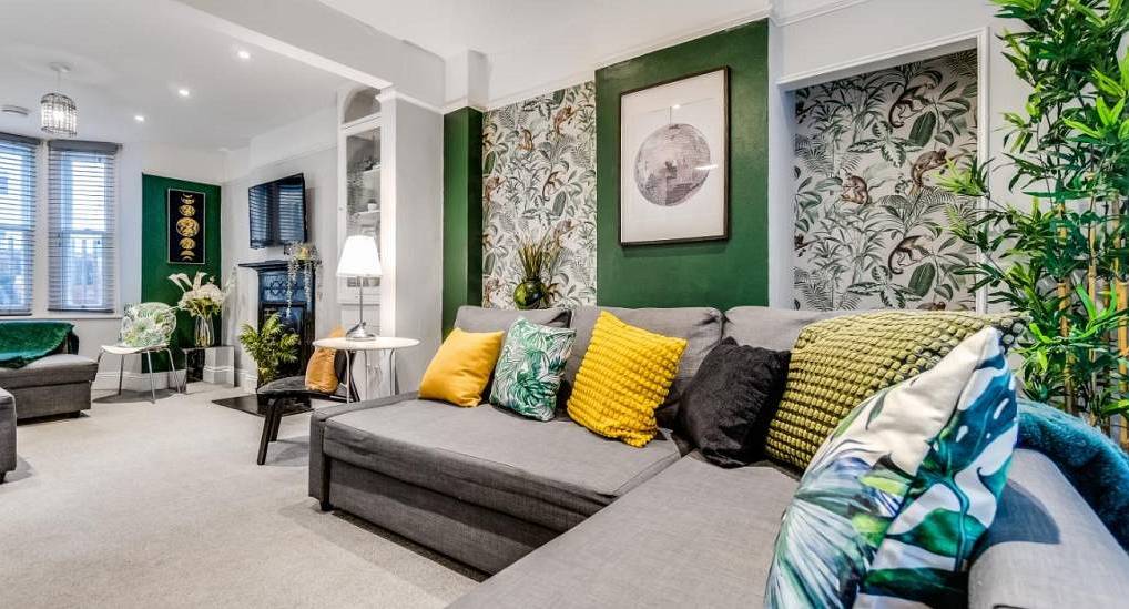 Botanical living room with jungle wallpaper and grey corner sofa at Pier Place, hen townhouse near Brighton Pier.
