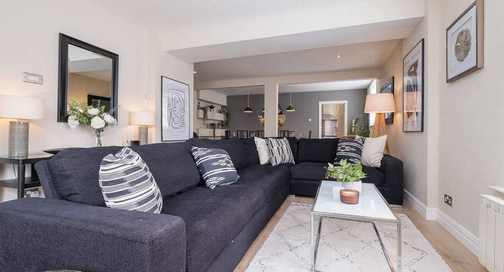 Boutique living room with dark L-shaped sofa, marble coffee table and line art at The Smarties, luxury Brighton house.