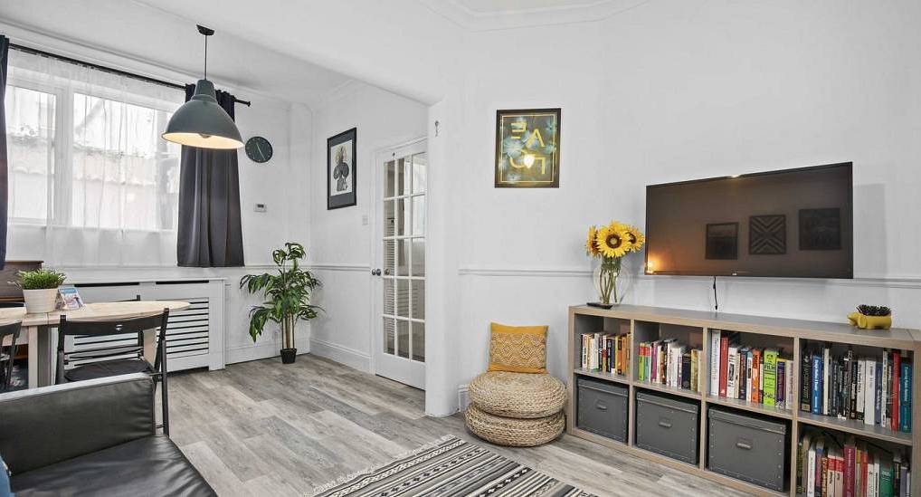 Bright living space with white walls, bookshelf storage and TV at Zoes Cottage, charming hen cottage near The Lanes.