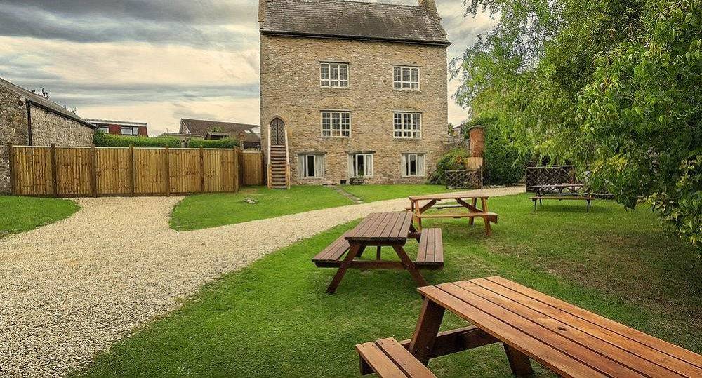 The 800-year-old stone manor building and lawn picnic tables at Mystery Mansion, a historic Bristol hen party house.