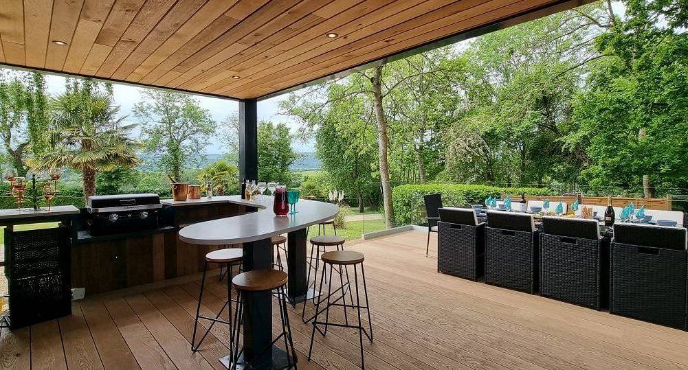 The covered wooden deck with outdoor bar and dining area at Retreat 12, a rural Bristol hen party cottage for 12.