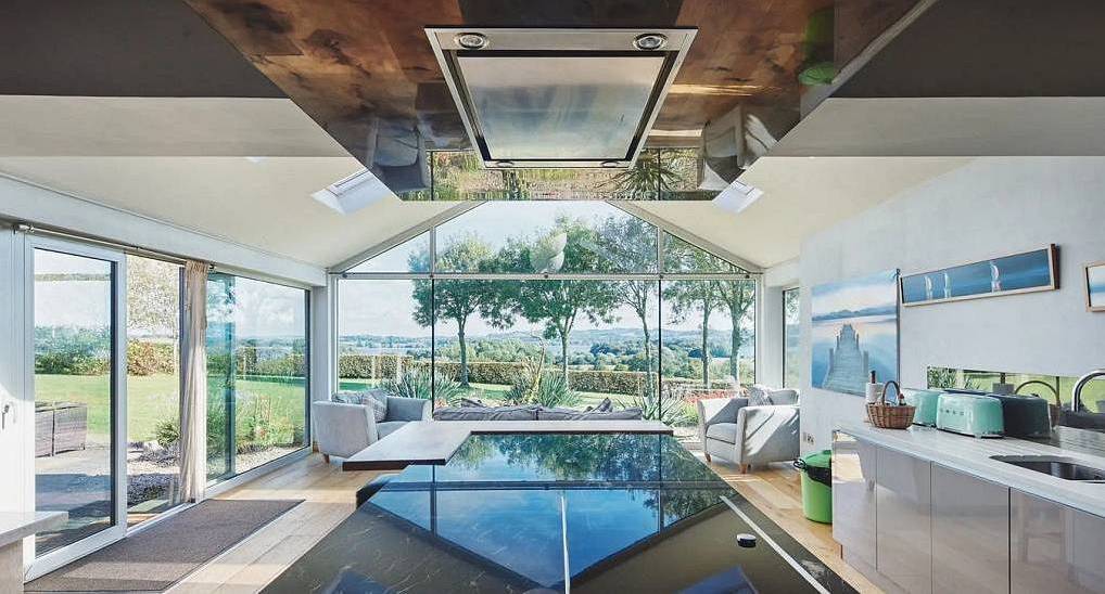 The contemporary sunroom with marble dining island and countryside views at Retreat 20, a Bristol hen cottage for 20.