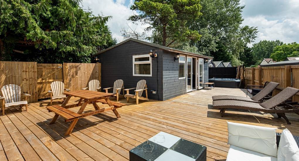 The wooden sun terrace deck with picnic table and loungers at The Acres, a hen party house near Bristol and Bath.