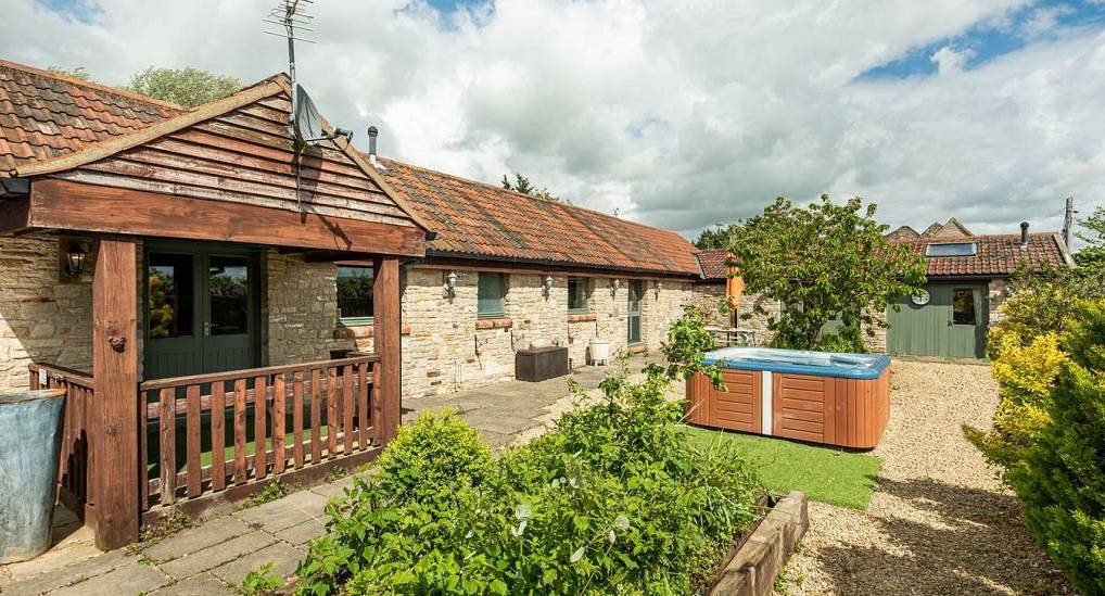 The stone barn building and gravel garden hot tub at The Stables, a converted Bristol hen party house sleeping 24.