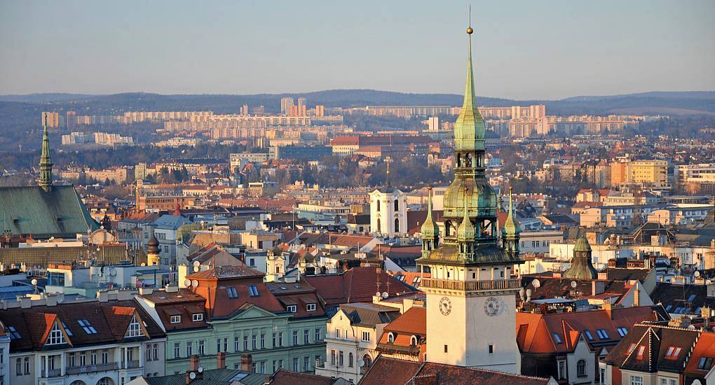 Old Town Hall tower with green spire overlooking red roofs in warm sunlight, scenic backdrop for a Brno stag do.