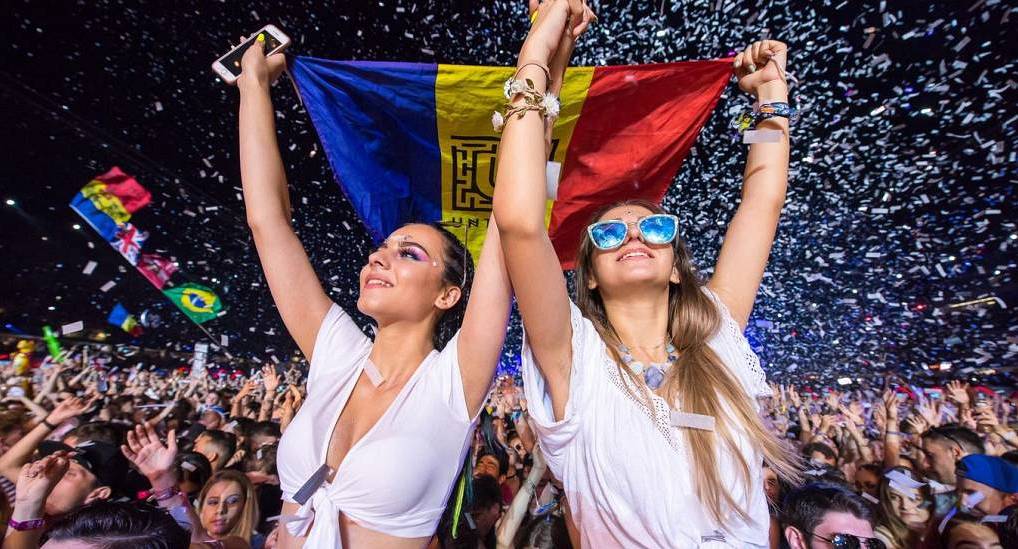Crowd at a nightlife club festival with falling confetti and Romanian flag, energetic setting for a Bucharest stag do.