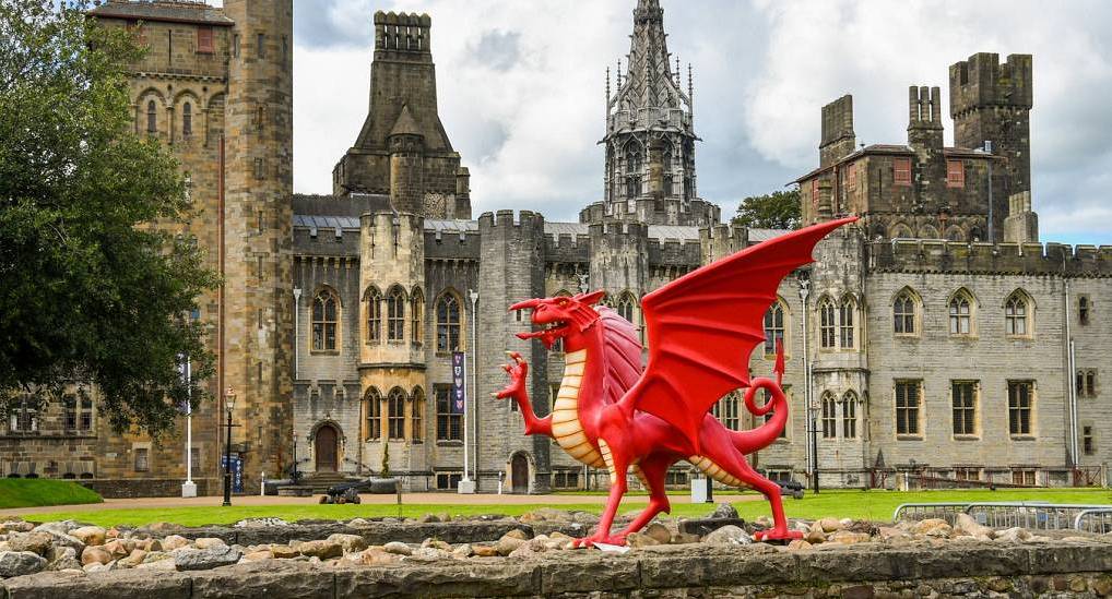 Red Welsh Dragon statue standing in front of historic Cardiff Castle, iconic setting for a Cardiff hen do.