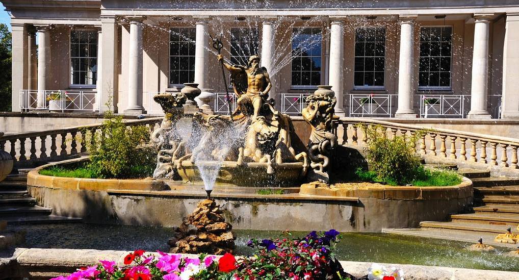 Neptune's Fountain with spraying water jets in front of Regency colonnade building, ideal setting for a Cheltenham hen do.