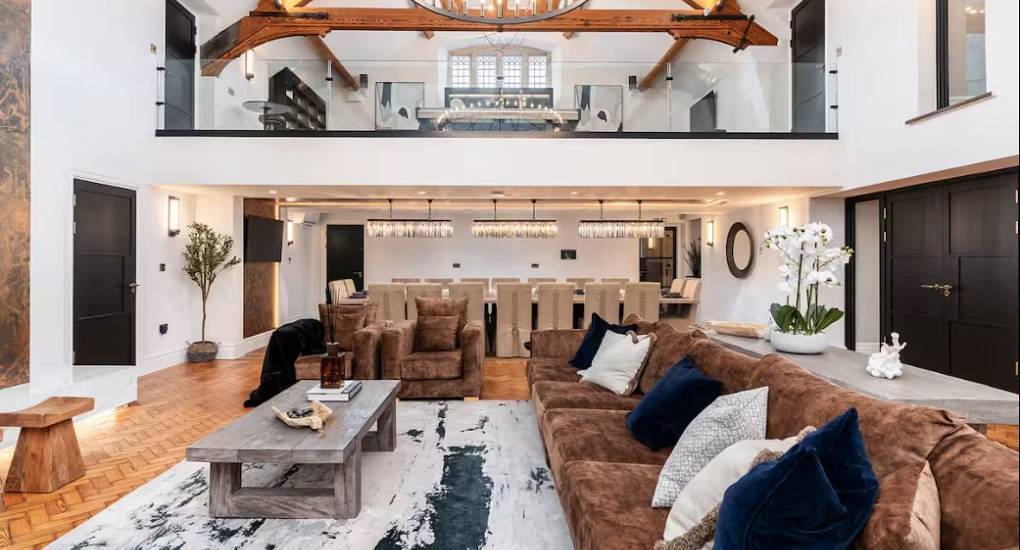 Grand double-height living room with plush brown sectional sofa and exposed wooden beams at House of Dreams Chester.
