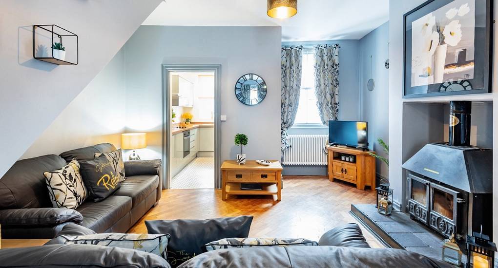 Cosy lounge with dark leather sofas, wood burning stove and blue-grey walls at King & Queen, central Chester hen house.