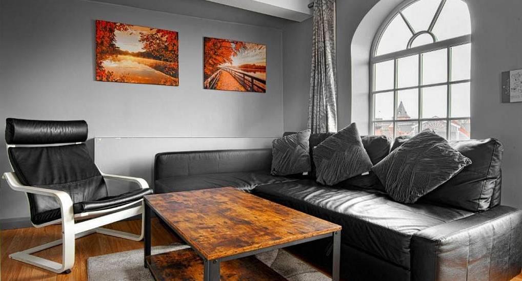 Lounge area with black leather sectional sofa, rustic coffee table and arched window at The Condo near Chester.