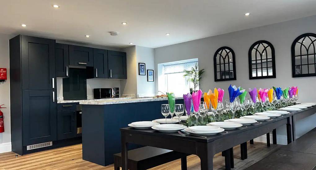 Navy blue kitchen and long dining table set with colourful napkins at The Rose, stylish Chester hen party house.