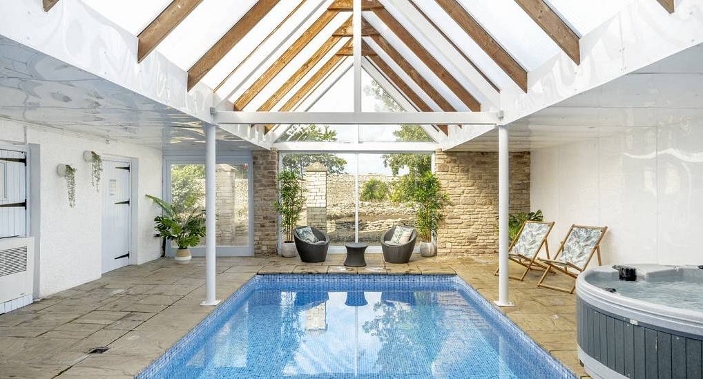 The glass roof indoor swimming pool and hot tub room at Stylish Retreat, a luxury Cotswolds hen party house near Bristol.