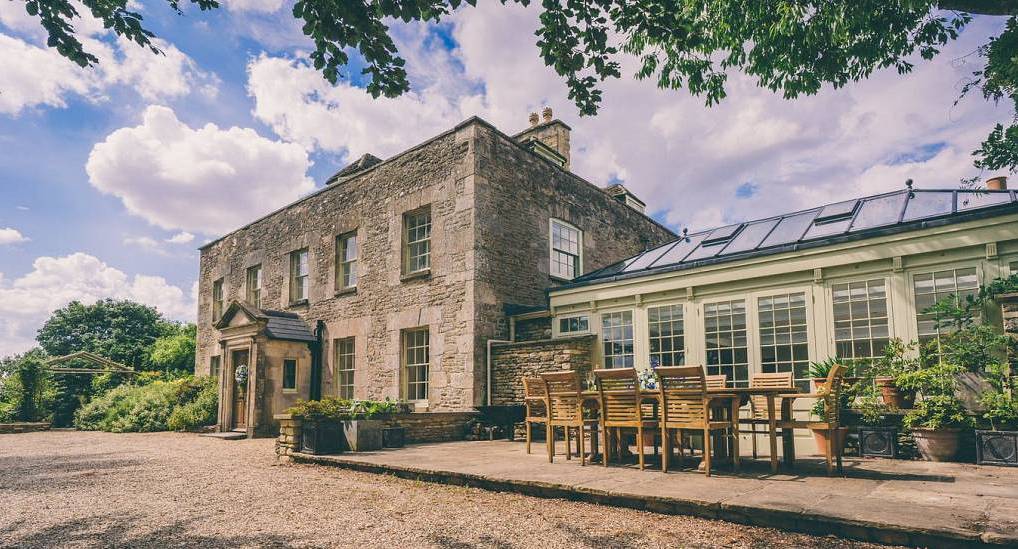 The historic stone manor house and orangery dining patio at The Great Barn, a Cotswolds hen party barn for 16.