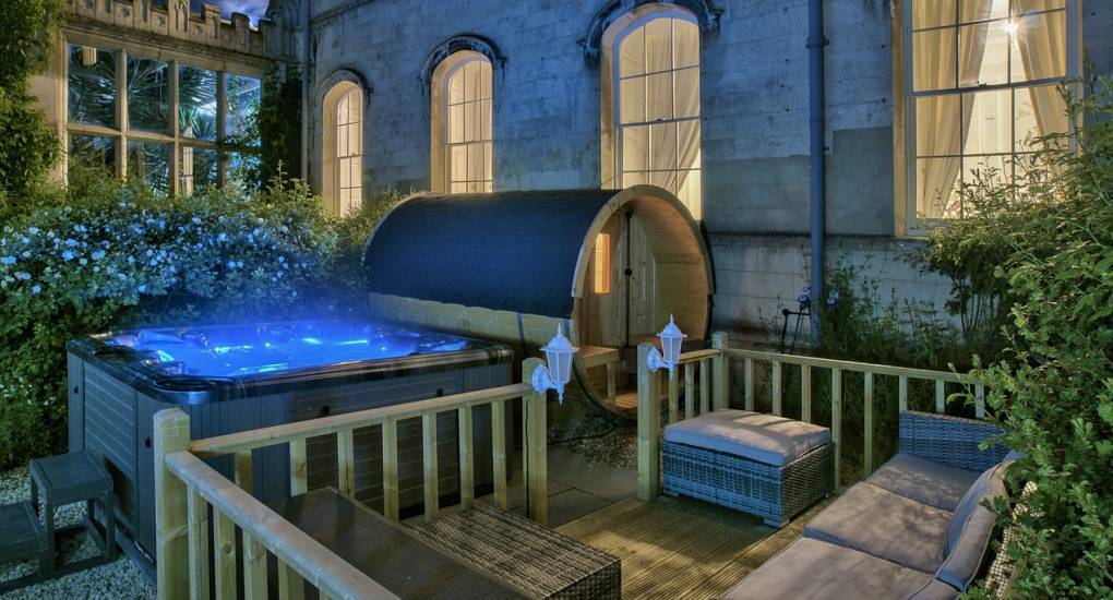 The luxury hot tub and sauna at Country Fortress illuminated at dusk, perfect for an evening spa retreat on a Newcastle hen do.