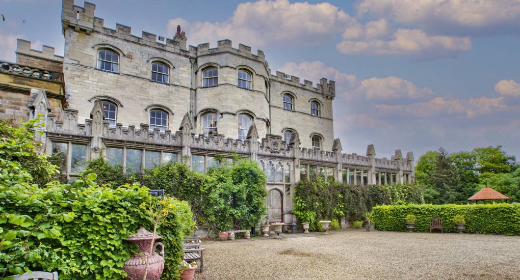 A side-angle view of the grand stone exterior at Country Fortress, a luxury Newcastle hen party manor house with private grounds for large groups.