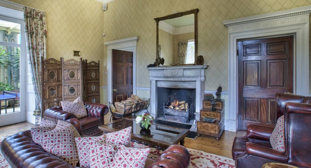 The cozy secondary reception room at Country Fortress featuring an open fireplace, perfect for a luxury Newcastle hen do weekend.