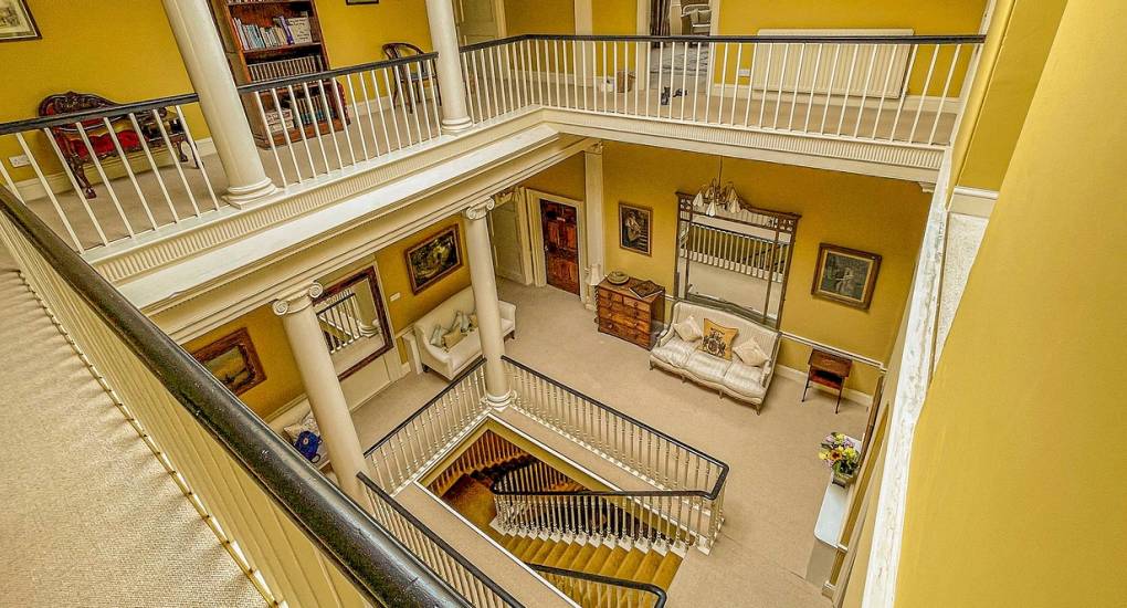 The grand square staircase at Country Fortress, a luxury Newcastle hen party manor house featuring spacious interiors across multiple floors.