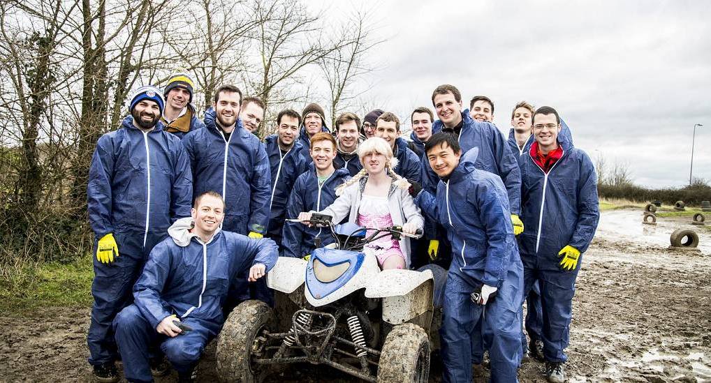 Group posing with mud and quad bike