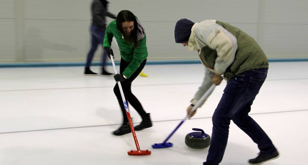 couple playing curling by sweeping the ice