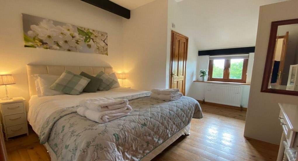 large bedroom with grey duvet set and wooden floor